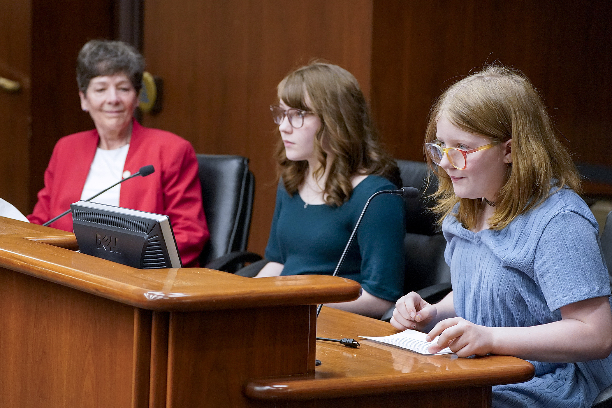 Winifred LaPorte, 11, right, testifies alongside her older sister Genevieve, 12, before the House veterans committee March 11, in support of HF4451. Rep. Peggy Bennett is the sponsor. (Photo by Michele Jokinen)